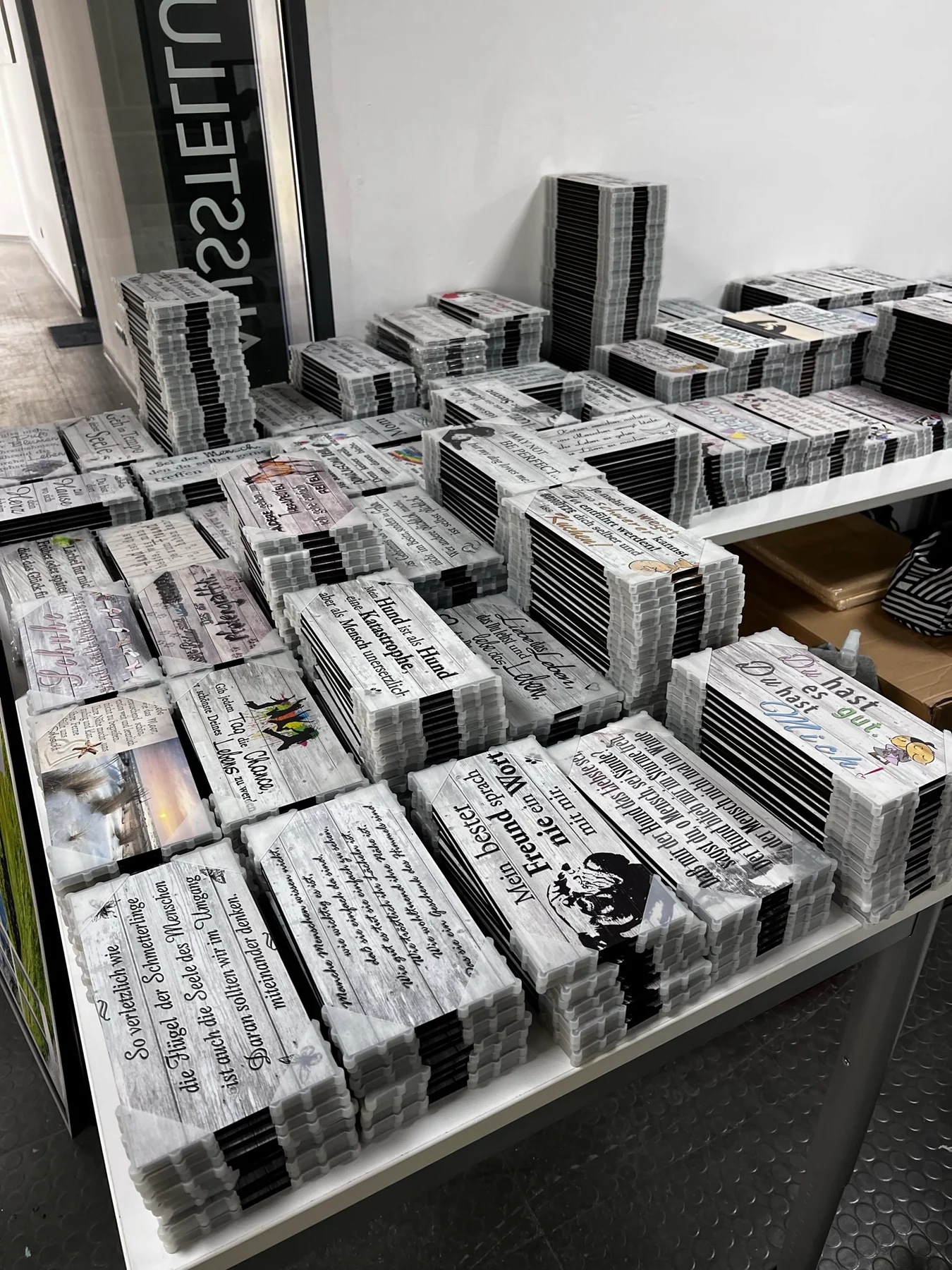 Große Mengen fertig bedruckter und geschützter Spruchschilder auf Packtischen